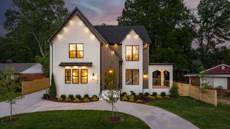 Two-story white and dark-trim exterior lit at twilight